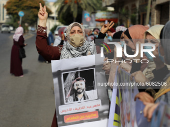Demonstrators, wearing protective face masks, hold pictures of hunger-striking Palestinian prisoner Maher Al-Akhras, who is held by Israel,...