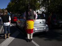 Demonstrators hold a constitutional Spanish flag  next to an in-vehicle protest against the Spanish government on Spain's National Day durin...