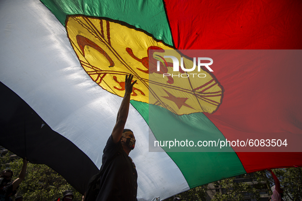 A person holds a large flag of the Mapuche nation-people, just below its great emblem  during a protest in the framework of the Day of the R...