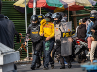 Riot police officers detain a protester who caused unrest during a rally to protest against the Omnibus Law in Magelang, Central Java, Indon...