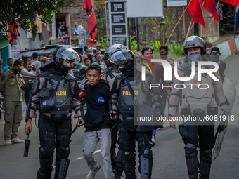 Riot police officers detain a protester who caused unrest during a rally to protest against the Omnibus Law in Magelang, Central Java, Indon...