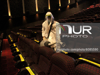 A worker sanities inside a theatre hall ahead of the scheduled reopening of cinema theatres on October 15 as the Covid-19 coronavirus impose...