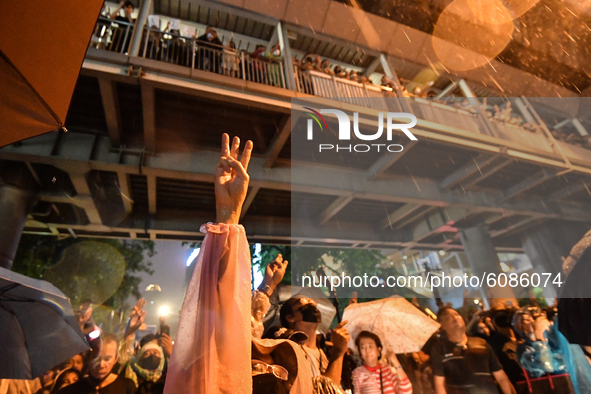 Pro-democracy protesters hold up three finger salute outside the Royal Thai Police Headquarters to protest the earlier arrest of protesters...