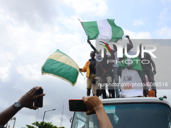 Youths of ENDSARS protesters display the Nigerian flag and a placard in a crowd in support of the ongoing protest against the harassment, ki...