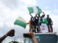 Youths of ENDSARS protesters display the Nigerian flag and a placard in a crowd in support of the ongoing protest against the harassment, ki...