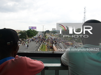 Two men watching Youths of ENDSARS protesters on top of a bridge during the ongoing protest against the harassment, killings and brutality o...
