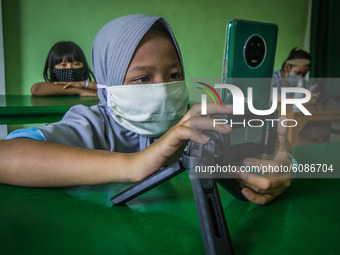 Students uses smartphones to work on online school assignments using free internet network while practicing physical distancing at the Rumah...