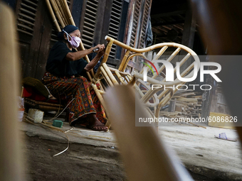An old woman weaving rattan to tie her elbows on a chair she crafted in Palembang, Indonesia on October 14, 2020. (