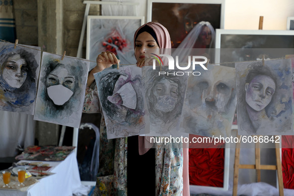 Palestinian artist Kholoud al-Desouki,27,hangs her paintings as she works during lockdown at home in Khan Yunis in the southern Gaza Strip,...