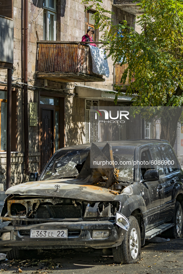 A woman in her balcony looks a destroyed car by azeri rocket during the shelling of Azerbaijan  army over Stepanakert, capotal of Nagorno Ka...