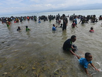 
A number of residents wet their bodies with sea water while participating in the Safar bathing ritual on Tumbelaka Beach, Palu City, Centr...