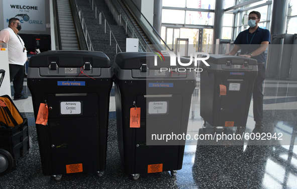 A worker brings tabulation machines to an early voting site established by the City of Orlando and the Orlando Magic at the Amway Center, th...
