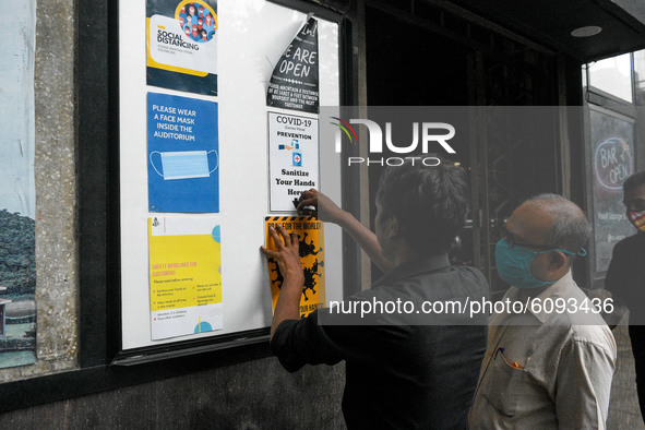Cinema hall staff hanging information on a notice board outside a movie theater in Kolkata, India, on October 16, 2020. Cinema halls are per...