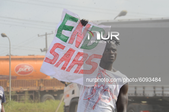 A Youth of End Sars Protesters hold a placard with description (END SARS) to barricade the Lagos - Ibadan expressway, the oldest highway and...