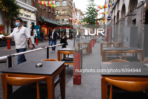 A man wearing a face mask walks past empty outdoor tables on Gerrard Street in Chinatown in London, England, on October 16, 2020. London is...