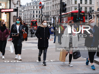 People wearing face masks cross Oxford Circus in London, England, on October 16, 2020. London is to be placed under 'Tier 2' coronavirus loc...