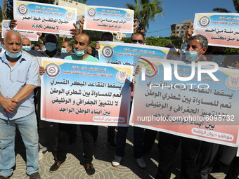 Palestinian Authority employees hold banners during a demonstration against Palestinian Government’s “obligatory and early retirement of emp...