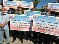 Palestinian Authority employees hold banners during a demonstration against Palestinian Government’s “obligatory and early retirement of emp...