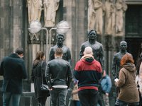 People with face masks look at the statues which was installed by a group of artists protest against US government in Cologne, Germany, on O...