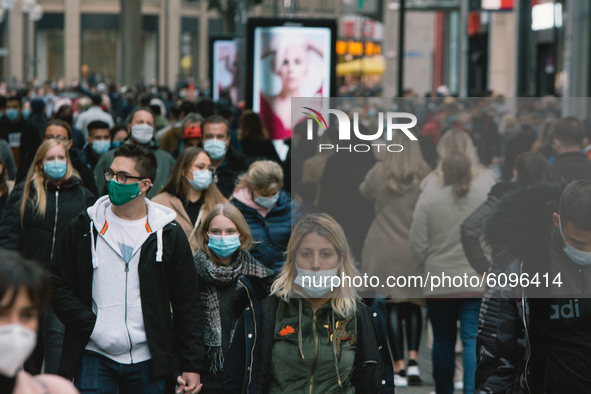 Crowd of people with face masks walking in the shopping block in Cologne, Germany, on October 17, 2020 as NRW state mandate face covering in...