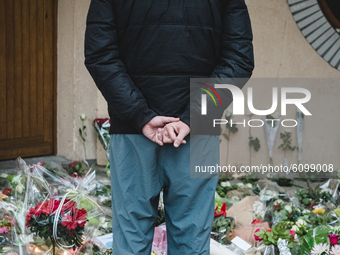 A man looks at flowers at the entrance of a middle school in Conflans-Sainte-Honorine, 30kms northwest of Paris, on October 17, 2020, after...