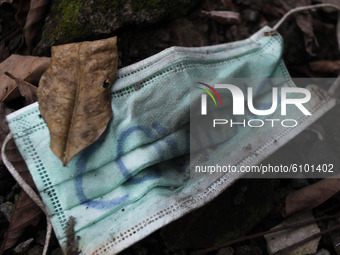 This is photo illustration, a disposable surgical face mask  is seen lying on a debris rock during the new coronavirus pandemic in Jakarta,...