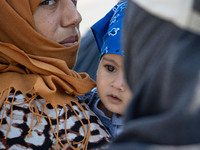 Close up of a mother holding her child near Moria refugee camp. Portraits of young children refugees, minors boys and girls, asylum seekers...