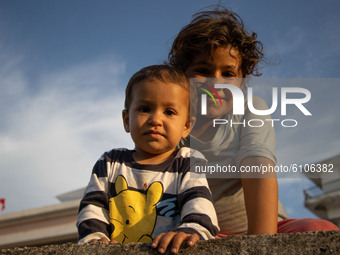 A girl and a boy, siblings living on the terrace of a building in tents after the fire. Portraits of young children refugees, minors boys an...