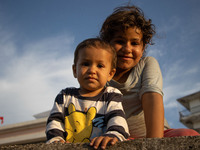A girl and a boy, siblings living on the terrace of a building in tents after the fire. Portraits of young children refugees, minors boys an...