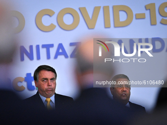 Brazil's President Jair Bolsonaro coughs next to Brazil's Chief of Staff Minister Walter Braga Netto during the COVID-19 Clinical Study resu...