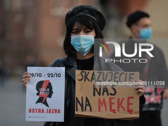 Pro-Choice activist holds 'Women Strike' poster and a sign that says 'You Condemn Us To Suffering', seen in the center of Krakow, part of th...