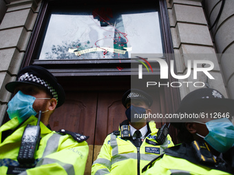 Police officers stand guard outside the egg- and paint-splattered Nigerian High Commission on Northumberland Avenue as activists protesting...