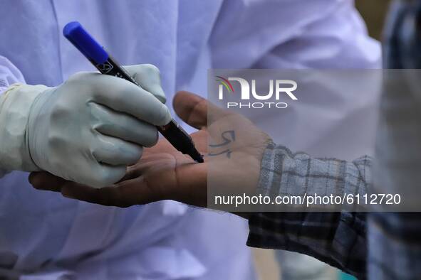 A health worker writes a number on the hand of a person who was tested negative for Rapid Antigen Test (RAT) for the COVID-19 coronavirus at...