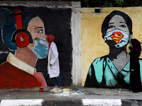 Palestinian artists give the final touches to a wall painting a coronavirus awareness in a street, amid the coronavirus disease (COVID-19) o...