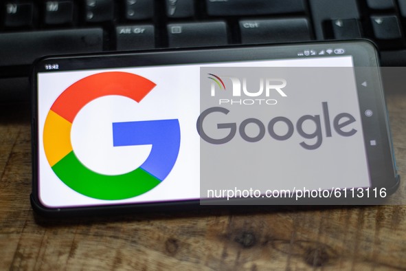 Google closeup logo displayed on a phone screen, smartphone on a keyboard is seen in this multiple exposure illustration, the company's symb...