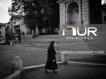Italy, Rome:  (EDITOR'S NOTE: IMAGE HAS BEEN CONVERTED TO BLACK AND WHITE) A nun wearing a face mask walks past piazza Trilussa in Trastever...