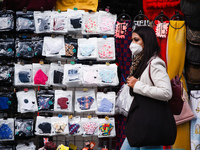 A woman wearing a face mask walks past a clothing stall selling patterned masks on Oxford Street in London, England, on October 22, 2020. Re...
