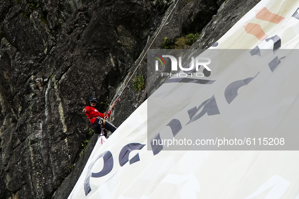 A woman is climbing a cliff to fly a large banner with the words Soempah Pemoeda on the Serelo hillside, Lahat Regency, South Sumatra Provin...