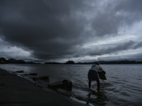 A fish vendor working in the banks of Brahmaputra river as dark clouds gather in the sky, in Guwahati, India on 23 October 2020. (