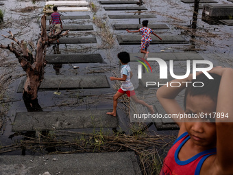 Children skip on submerged tombs inside a public cemetery in Pampanga province, north of Manila on October 24, 2020. Low-lying villages in t...
