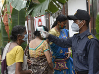 Security personnel thermal screeing a devotee before enter to a puja pandal, during Durga puja festival, in Guwahati, India on 24 October 20...