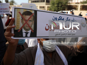Palestinian demonstrators lift placards showing a crossed out picture of French President Emmanuel Macron during a protest against the publi...