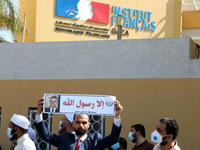 Palestinian demonstrators lift placards showing a crossed out picture of French President Emmanuel Macron during a protest against the publi...