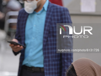 An Iranian woman and a man wearing protective face mask to prevent themselves of infection by the new coronavirus disease (COVID-19) in Tehr...
