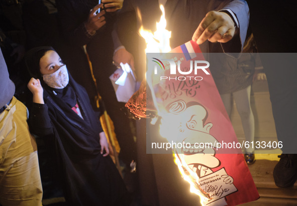 An Iranian protester burns a cartoon of the French President Emmanuel Macron during a protest gathering in front of the French embassy in Te...