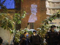 A cartoon of the French President Emmanuel Macron is projected on a wall of the French embassy as Iranian policemen stand guard during a pro...
