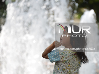 A girl plays in a fountain to cool down in the hot weather in Tokyo May 31, 2015.  (