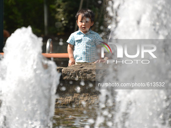 A boy plays in a fountain to cool down in the hot weather in Tokyo May 31, 2015.  (