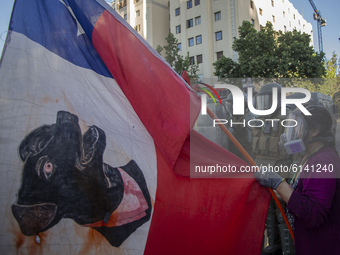 A person holds a Chilean flag, with a drawing of the dog -Negro Matapacos-, whose image became an emblem of the protest  on October 30, 2020...