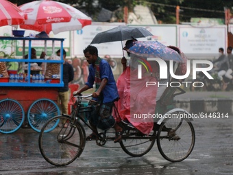People ride on a rickshaw during rainfall in Dhaka, Bangladesh on November 1, 2020. (